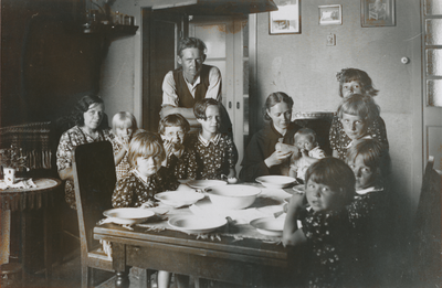 876914 Afbeelding van een Zuster Augustines die als gezinshulp werkt bij een gezin met negen kinderen, vermoedelijk in ...